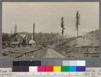 View toward read end of mill, showing sorting table, refuse conveyor, open fire pit, lumber pile foundations in foreground. Spanish Peak Lumber Company, Quincy, California. August, 1920. E.F