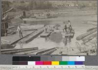 Bringing a large sinker log (redwood) to the log haul-up slip. Note the method of unloading logs at the left. Cars pass under the "gate" log and the load is thus pushed off into the pond. Northern Redwood Company, Korbel, California. May, 1920. E.F