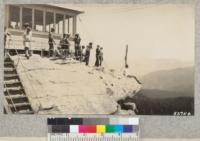 Neil Derrick perches on an edge of Buck Rock and views the high Sierras. Kings-Tulare 4-H club camp, Whitaker's Forest. July, 1930