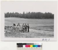 Alder firewood piled at the Liegel Brothers' place near Olympia, Washington. The meadow and timberland in background. Inspected for Farm Forestry group--Lunnum, Hopkins, Thomson, Kingsbury, and Lloyd. Metcalf. September 1952