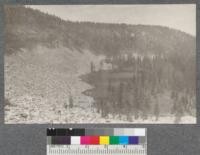 Honeysuckle Lake in most westerly glacial cirque at head of American Creek watershed. Ridge in background is between American and Canuck Creeks. Timber is Lyall Larch in foreground. Alpine Fir and Engelmann Spruce in background. Montana 1920. Metcalf