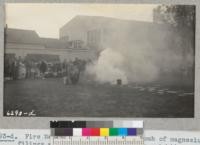 Fire Warden Dallas works on a bomb of magnesium filings at Hichman [Hickman?] High School demonstration after Metcalf and Grah had discussed hazards and fire fighting. Many farm firemen attended. Metcalf