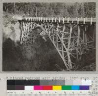 3-hinged redwood arch bridge, 150' span, 150' above creek. Rock Creek 25 miles south of Garberville, California. In process of repair after break of lower chord, left, at upper hinge. In service 21 years. Designed for 10 tons but loaded to 25 and 30 tons. See also #6624. 4-27-37. E.F