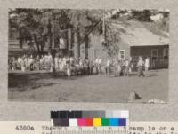 The San Diego-Imperial camp is on a Forest Service "special use" site in the Laguna Mountains. The cabin cost $1500 and is very comfortable, as cooking is done in one end, while tables for 100 occupy the main room. The crowd is here shown washing dishes after a meal. The forest is a very pretty open stand of Jeffrey Pine and Black Oak. Metcalf. July, 1928