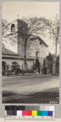 Black locusts at entrance to Mission San Juan Bautista, San Benito County. Metcalf. 1928. (December)