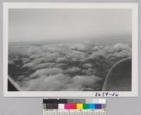 Clouds from the plane over Coast Range with line of snow of the Sierras in the background. Metcalf. December 1952