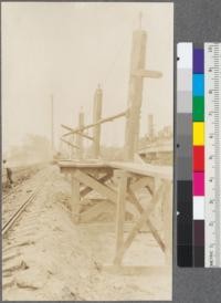 Gill-poke method of unloading log cars. Note that track inclines toward log pond. The man is leaning over the pond bulwark, over which the logs roll into the water. Union Lumber Company, Fort Bragg, California. May, 1920. E.F