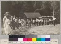 Miss Kirchner - "Chieftess Black Swan" - giving the orders of the day to the Kings-Tulare girls after flag-raising at Whitaker's Forest. Metcalf. July, 1928