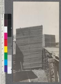 A well built pile of lumber 1x12x18 White Fir 33910 feet. Note slight forward rake to pile, good slope of top, roof fastened on with wire, stickers 1-5/8x4, central tier vertical. Weed Lumber Company, Weed, California. June, 1920. E. F