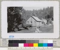 Using Army truck to do grading in front of the new "Clover Cabin" built in 1948. Clyde drives the truck and Browning handles the scraper. Redwood Cabin in background. Metcalf