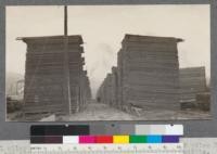 A full alley of "California White Pine" shop lumber. 43 piles long, about 800,000 board feet of lumber. 6/4 #2 shop all widths. Piles average about 19000 feet each. Machine piled, note nearly flat top and roof. McCloud River Lumber Company, McCloud, California. June, 1920. E.F