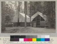 A view of the style of tent house built in 1926 at Camp Califorest. The floor measures approximately 10x12' and the walls are 3' high. The tent on the right is the first one built. The tent on the left, the second. Notice the double deck bunk in the open tent, made by supporting a standard steel cot on 2x4's above another cot resting on the floor