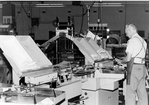 Postal employee operates feeder machine