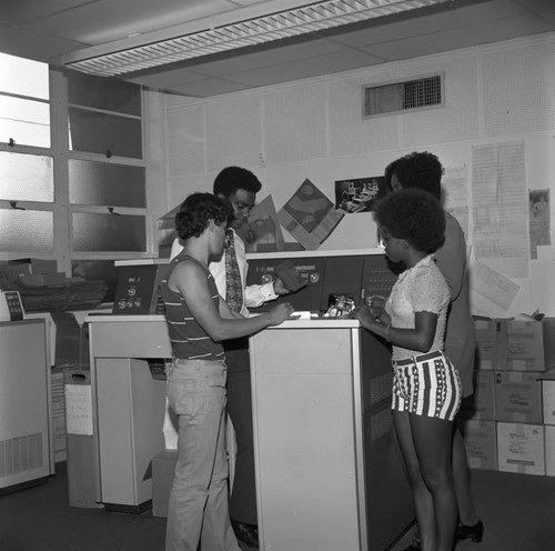 Students feeding keypunch cards into a card reader at Compton College, Compton, 1972