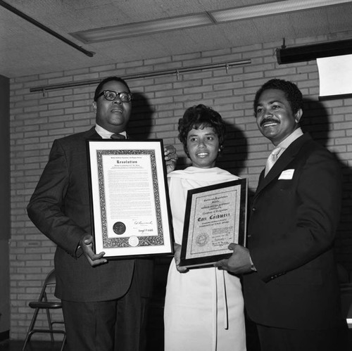 A. S. "Doc" Young holding a plaque while posing with Connie King and Mervyn Dymally, Los Angeles, 1970
