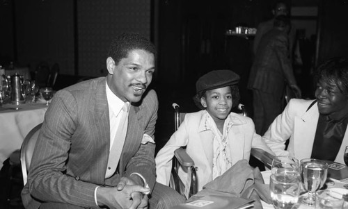 Marques Johnson sitting at the NBA All-Star Game dinner with a boy in a wheelchair, Los Angeles, 1983