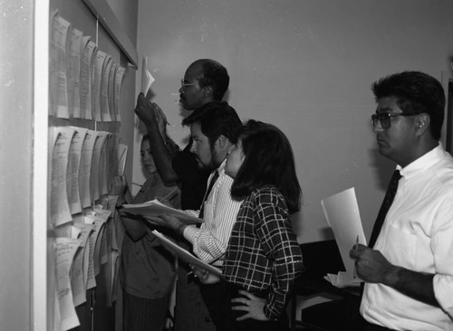 California Chicano News Media Association members examining postings, Los Angeles, 1994