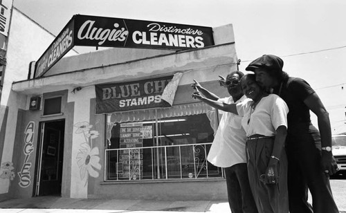 Augie Johnson and his parents pointing to Augie's Distinctive Cleaners, Los Angeles, 1983