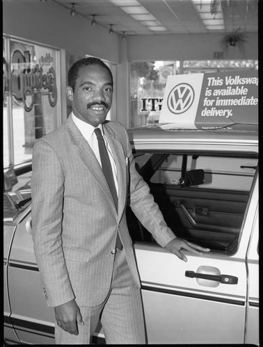 African American automobile dealer posing near a car, Los Angeles, 1983