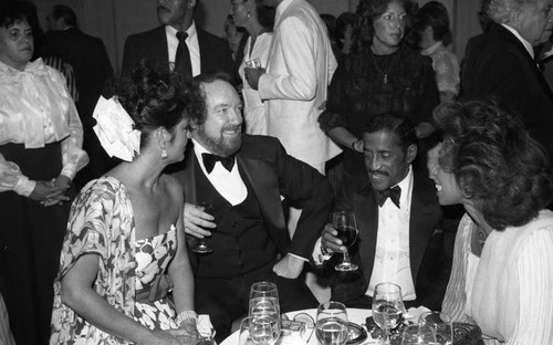 Sammy Davis, Jr. talking with an unidentified couple at a formal event, Los Angeles, 1983