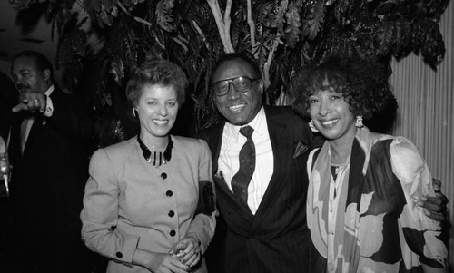 Unidentified man posing with two women during a Los Angeles Football Classic promotional event, 1989