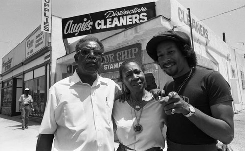 Augie Johnson and his parents standing in front of Augie's Distinctive Cleaners, Los Angeles, 1983