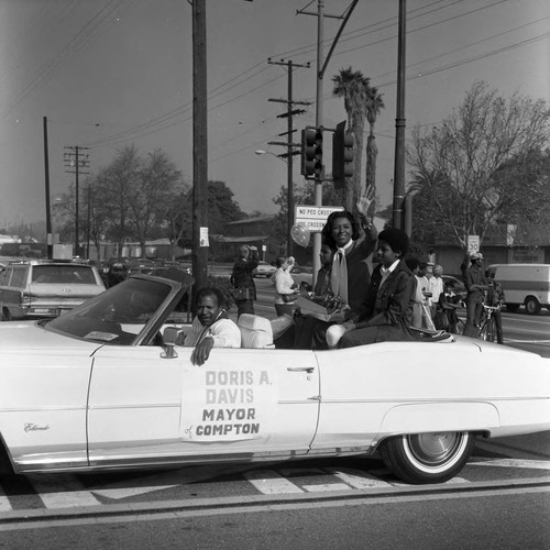 Watts Christmas Parade participant Mayor Doris A. Davis waves from a convertible, Los Angeles, 1975