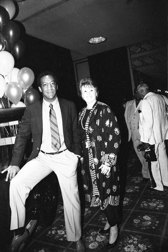 Bill Cosby posing with an unidentified woman at a Neighbors of Watts benefit, Los Angeles, 1982