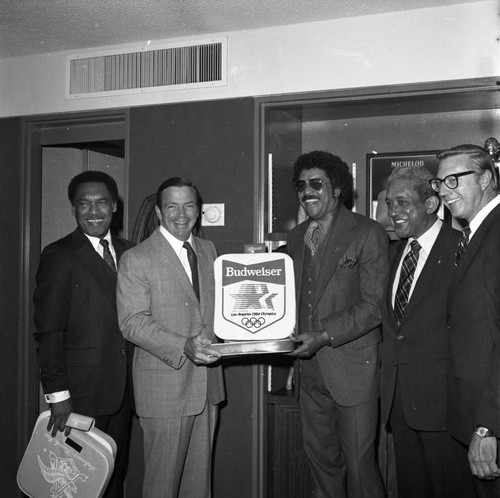 August Busch, III and others displaying a 1964 Olympics seat cushion, Los Angeles, 1982