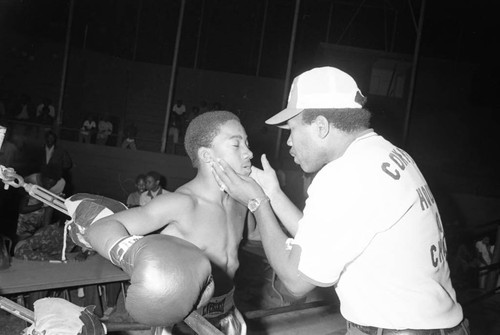 A trainer talks in the ring with a young boxer, Los Angeles, 1974