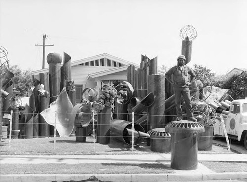 Lew Harris standing on an outdoor sculpture from "The Tenth Wonder of the Word" display, Los Angeles, 1984