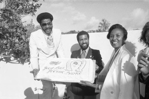 Yvonne Brathwaite Burke and others holding a cake, Los Angeles, 1980