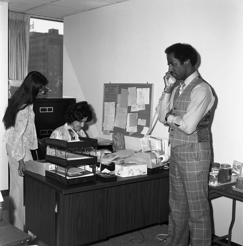 Donald Bohana talking on a phone in an office, Los Angeles, 1976