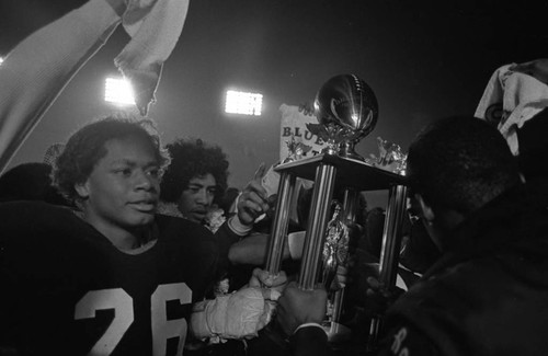 Carson High School football team members holding the city 4-A championship trophy, Los Angeles, 1982