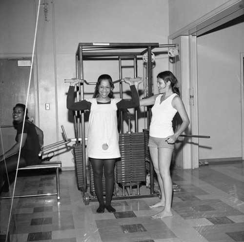 Young women lifting weights in Compton College gym, Compton, 1972