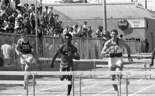 Spectators watching student athletes clear hurdles during a track meet, Los Angeles