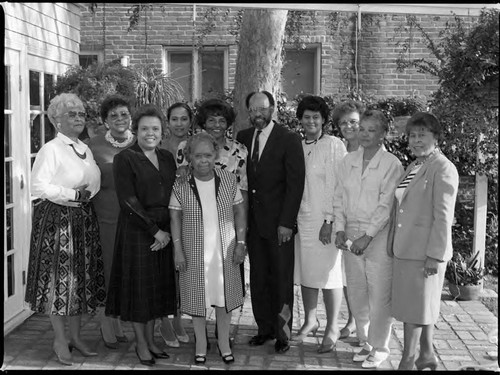 Ten women pose together with a man on an outdoor patio, Los Angeles, 1989