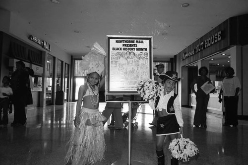 Young girls in costume posing with a Black History Month sign at a mall, Los Angeles, 1982