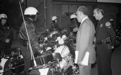 Jesse Brewer talking with LAPD police officers near their motorcycles, San Pedro, California, 1982