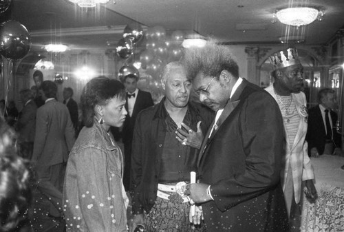 Don King talking with a couple at a press conference for the "Crown Affair" boxing event, Los Angeles, 1983