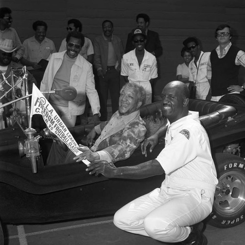 Redd Foxx sitting in an antique car during the Urban League Celebrity All-Star Freedom Classic pre-game, Los Angeles, 1973