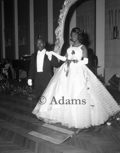 Debutante Jamia Glenn walking through a "portraits of loveliness" frame at a cotillion, Los Angeles, 1964