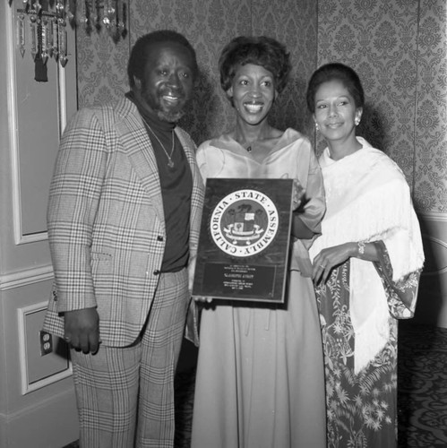 Maxine Waters posing with Clarence and Jacqueline Avant as she presents an award, Los Angeles, 1978