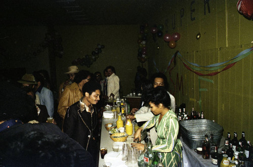 Herb Thompson and a bartender serving drinks at a Super Bowl party, Los Angeles, 1977