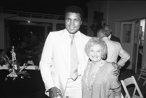 Muhammad posing with a guest at an Olympic Arts Festival cast party, Los Angeles, 1984