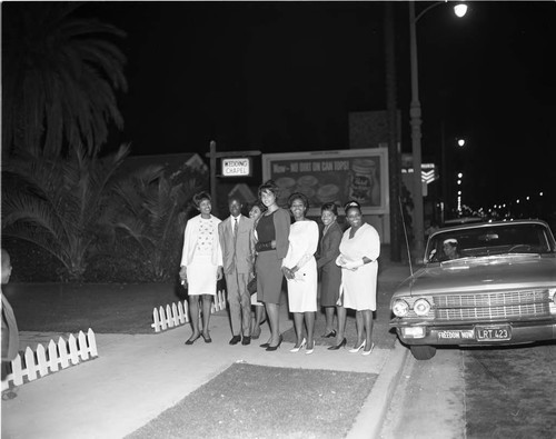 Bride and groom posing with others in front of a wedding chapel, Los Angeles, 1965