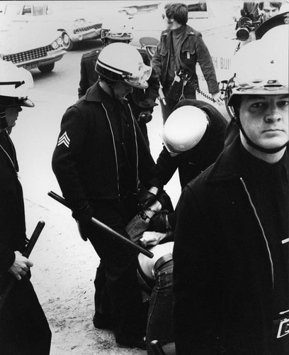 Policemen handcuffing a man in the street, Los Angeles, 1969