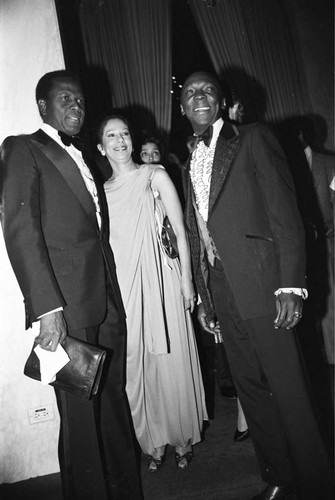 Sidney Poitier posing with an unidentified couple at a Neighbors of Watts benefit, Los Angeles, 1982