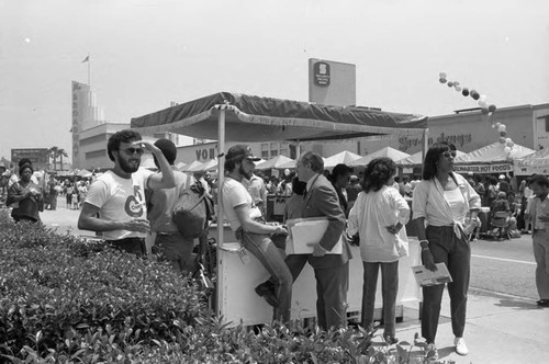 People gathering at a booth on Crenshaw Blvd. during a street festival, Los Angeles, 1983