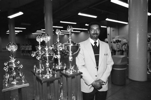 Man guarding trophies at the 9th Annual LAUSD Band and Drill Team Championship, Los Angeles, 1983